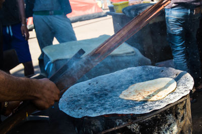 Cropped hand of man cooking food on stove at refugee camp