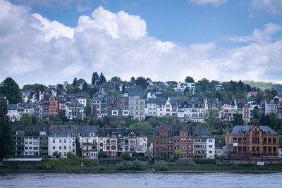 Buildings by river against sky in town