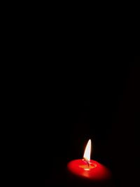 Close-up of illuminated candle against black background