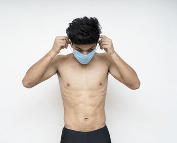 Full length of shirtless man standing against white background