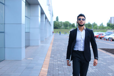 Young businessman standing against building