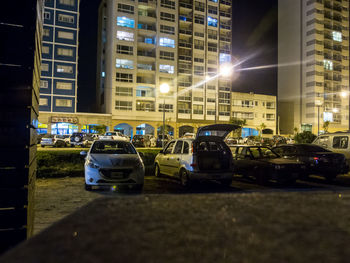 Cars on city street by buildings at night