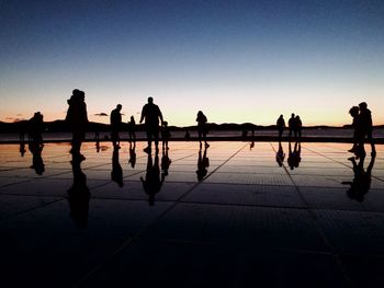 Silhouette people on sidewalk against sky during sunset - salutation to the sun in zadar croatia