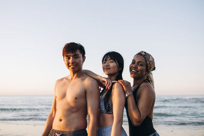 Portrait of shirtless young woman standing at beach