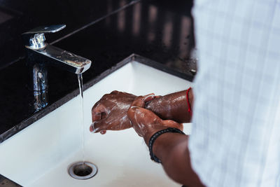 Midsection of woman cleaning hands in sink