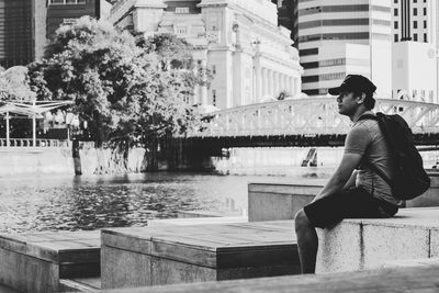 Full length of woman sitting against building in city