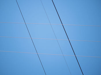 Low angle view of power lines against blue sky