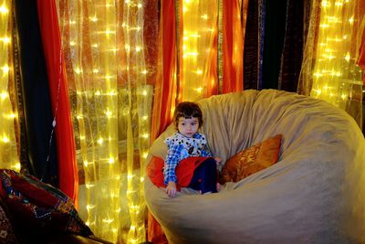 Girl sitting on sofa in illuminated room