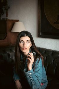 Young woman using mobile phone while sitting at home