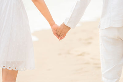 Low section of couple standing on beach