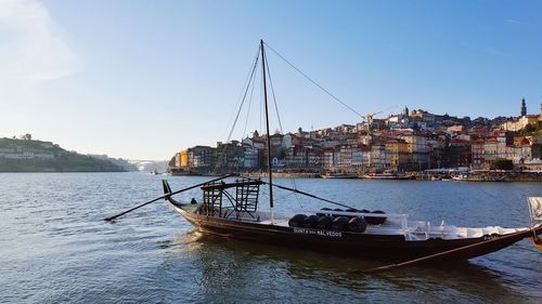 Boats in river by cityscape against sky