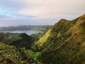 Scenic view of landscape by sea against sky