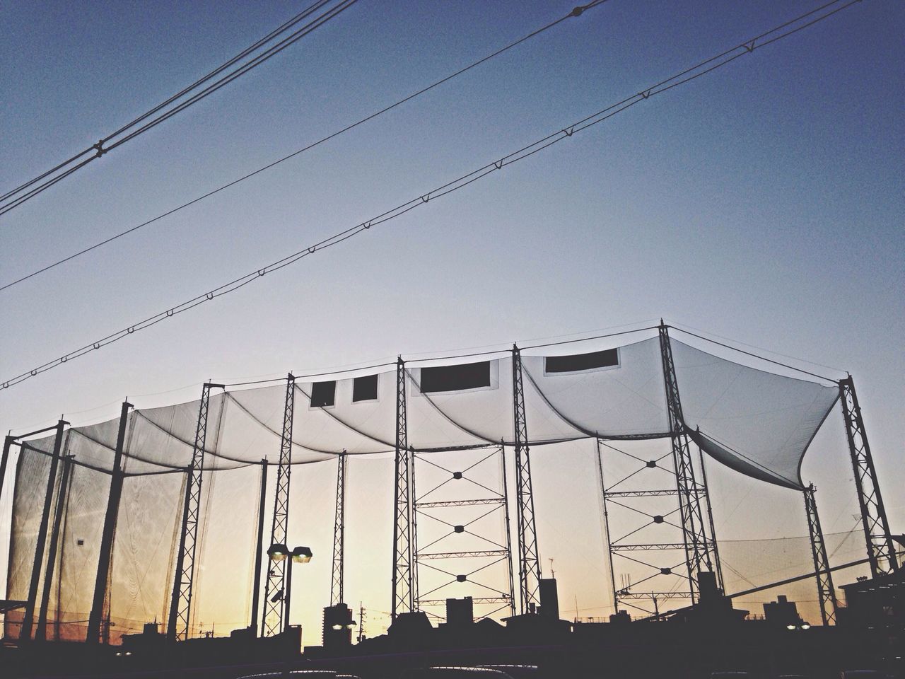 low angle view, power line, connection, clear sky, built structure, cable, architecture, silhouette, sky, electricity pylon, electricity, building exterior, power supply, dusk, outdoors, technology, no people, copy space, power cable, day