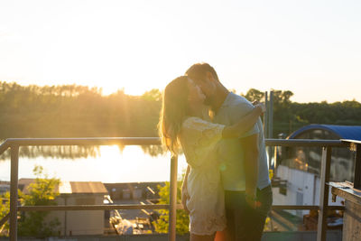 Couple kissing against sky during sunset