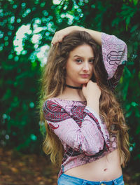 Portrait of beautiful young woman standing against trees