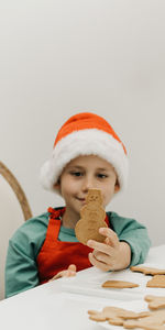 The kid is holding a gingerbread cookie in the shape of a snowman. cooking christmas cookies.
