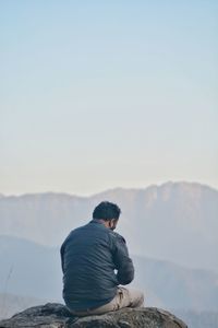 Rear view of man looking at mountain against sky