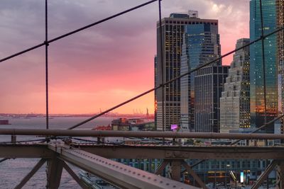 Modern bridge and buildings against sky during sunset