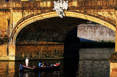 Tourists riding in boat on arno river under ponte santa trinita