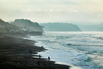 Scenic view of sea and silhouette people against sky