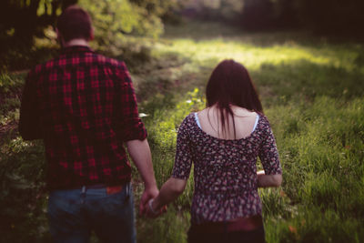 Rear view of couple walking on field