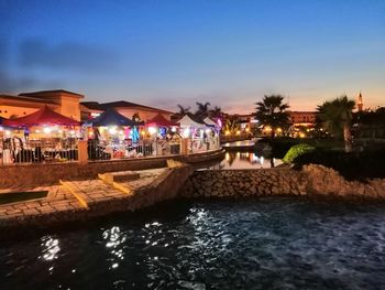 Swimming pool by river against sky at night