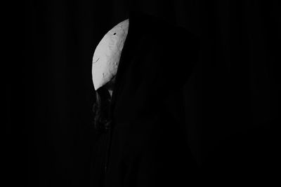 Side view of person standing against black background