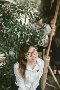 Portrait of young woman standing by plants