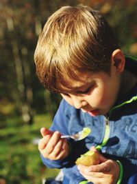 Cute boy eating fruit in sunny day