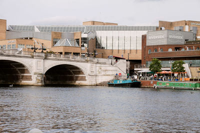 Arch bridge over river against buildings in city