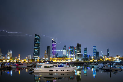 Illuminated modern buildings in city against sky at night