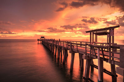 Pier over sea against sky during sunset