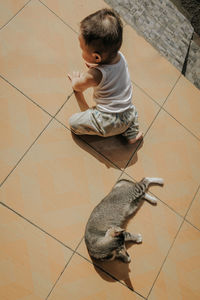 High angle view of child on floor at home with cat