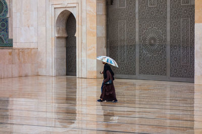 Couple with umbrella walkibg in hassan ii mosque square in a rainy day 