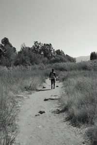 Rear view of person walking on dirt road