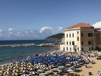 Buildings by sea against blue sky