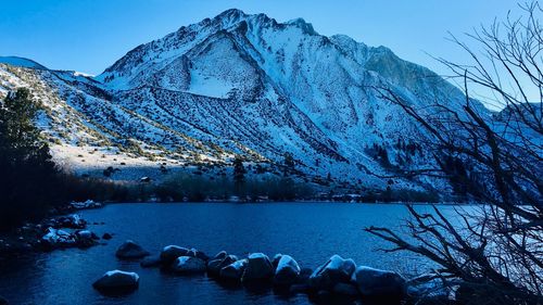 Scenic view of lake by snowcapped mountains against sky