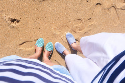 Low section of people relaxing on sand at beach