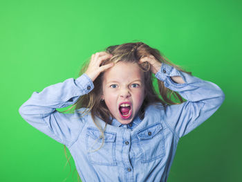 Angry girl against green background