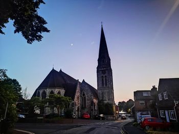 Cars on road by buildings against sky in city