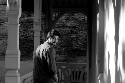 Side view of woman looking through window