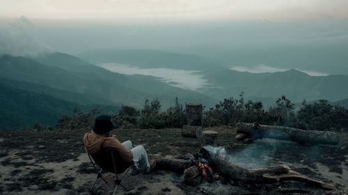 A man is sitting on the peak by the bonfire