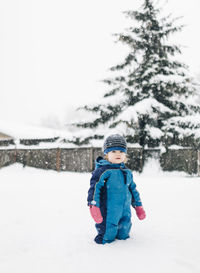 Rear view of boy in snow against sky during winter