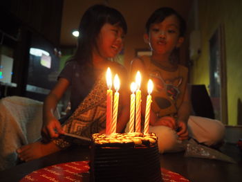 Low angle view of siblings with birthday cake sitting at home