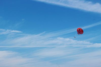 Low angle view of red parachute flying in sky