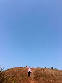 Full length of girl standing on ground against blue sky