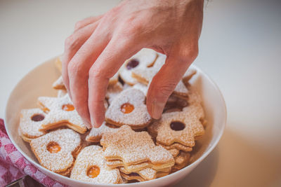 Person taking a cookie from the bowl against white background