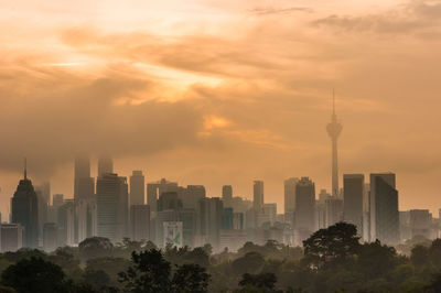 Modern buildings in city against sky during sunset