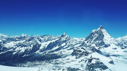 Scenic view of snowcapped mountains against clear blue sky