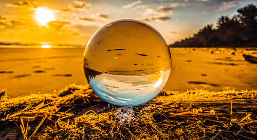 Close-up of crystal ball on glass against sky during sunset